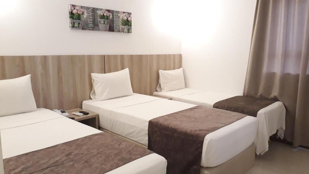 A hotel room with two beds, a nightstand, and a wall-mounted artwork.