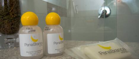 Dos botellas de champú y acondicionador, una pastilla de jabón y un recipiente de vidrio con plantas secas sobre una encimera de baño.