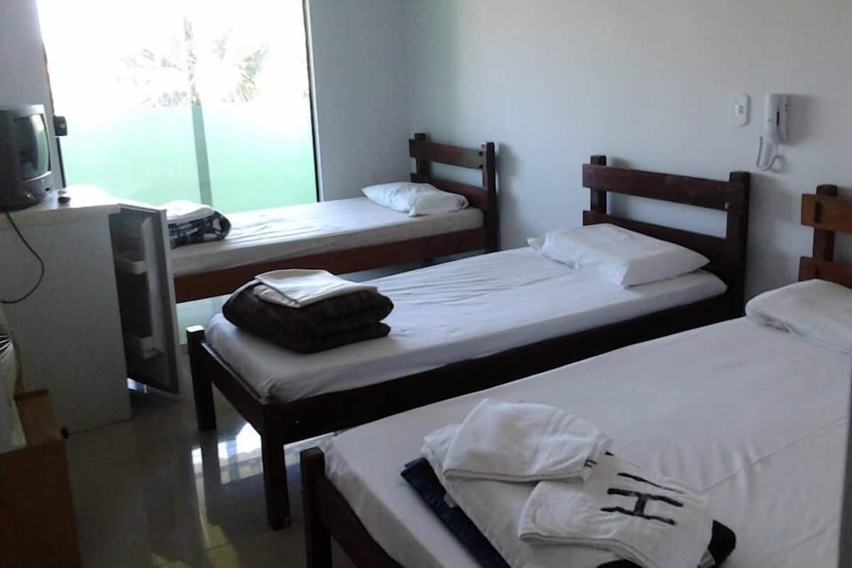 Une chambre avec deux lits simples, un bureau avec un ordinateur et une fenêtre donnant sur l’extérieur.