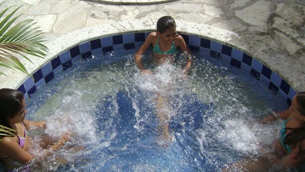 A swimming pool with a checkered edge, surrounded by stone tiles. - Hotel Imperador (Caldas Novas)