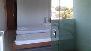 A small, single-room accommodation with a bed, a door, and a view of the outside. - Hotel Imperador (Caldas Novas)