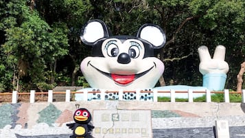 A large Mickey Mouse statue with a peace sign, a bird mascot, and a plaque with Chinese characters.