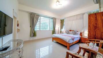 A bedroom with a bed, bedside table, and a glass table with chairs.