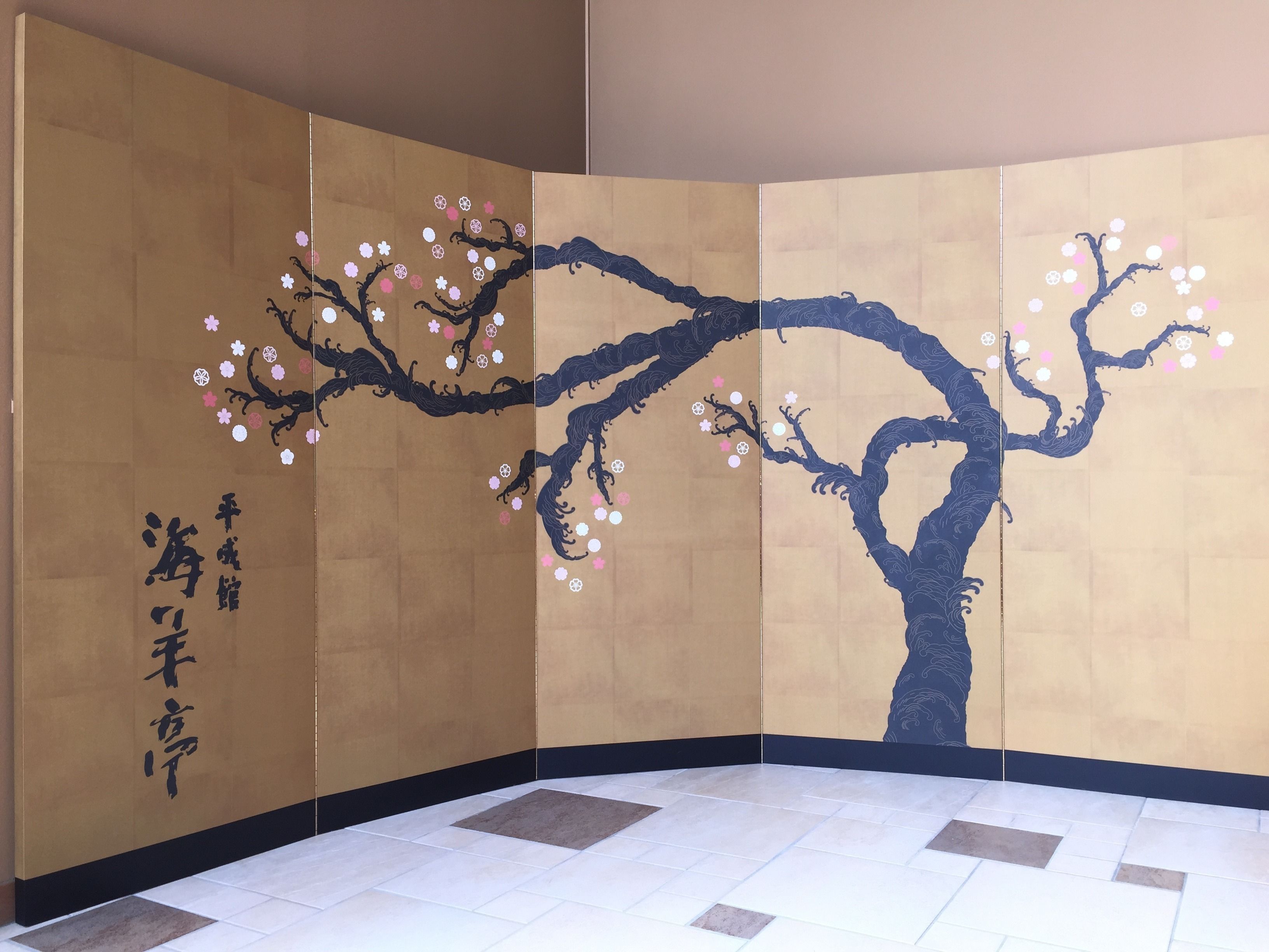 Una habitación con un tradicional panel japonés shoji decorado con flores de cerezo y caligrafía.