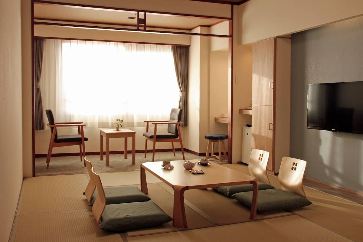Una tradizionale stanza in stile giapponese, con pavimento in tatami, un tavolino e disposizione dei posti a sedere.