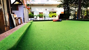 Una mesa de billar con superficie de fieltro verde, rodeada por un borde de ladrillo.