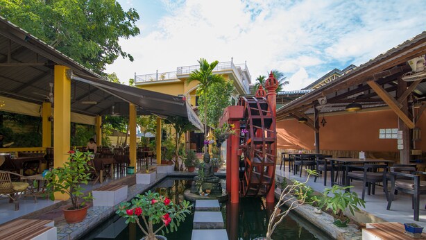 Un patio con fuente central, plantas en macetas y zonas de estar al aire libre.