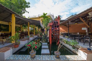 Un patio con fuente central, plantas en macetas y zonas de estar al aire libre.
