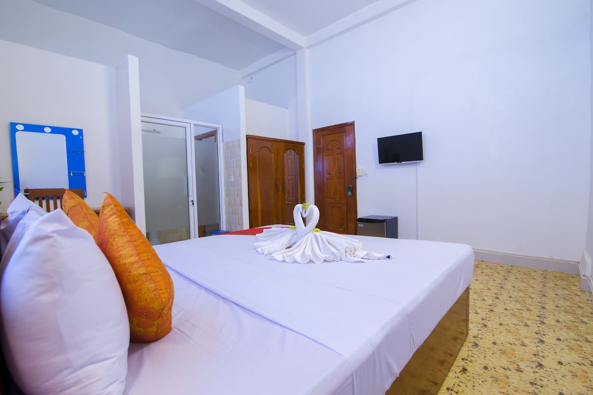 Ein Hotelzimmer mit Bett, Kissen, einem Spiegel, einem Fernseher und einem Kleiderschrank.