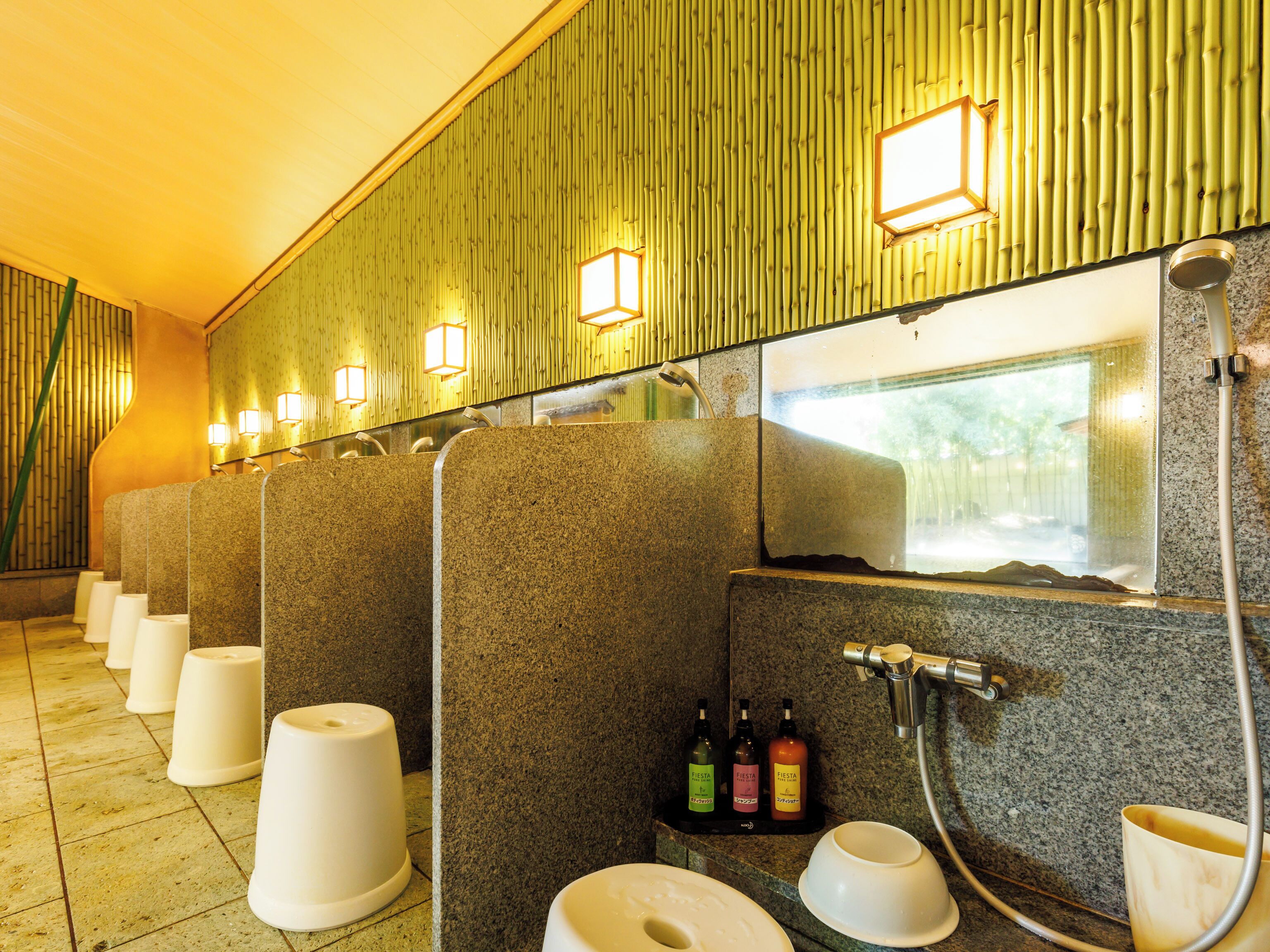 A restroom with multiple stalls, a sink, and a mirror.