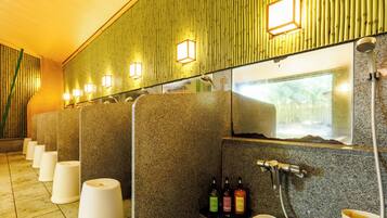 A restroom with multiple stalls, a sink, and a mirror.