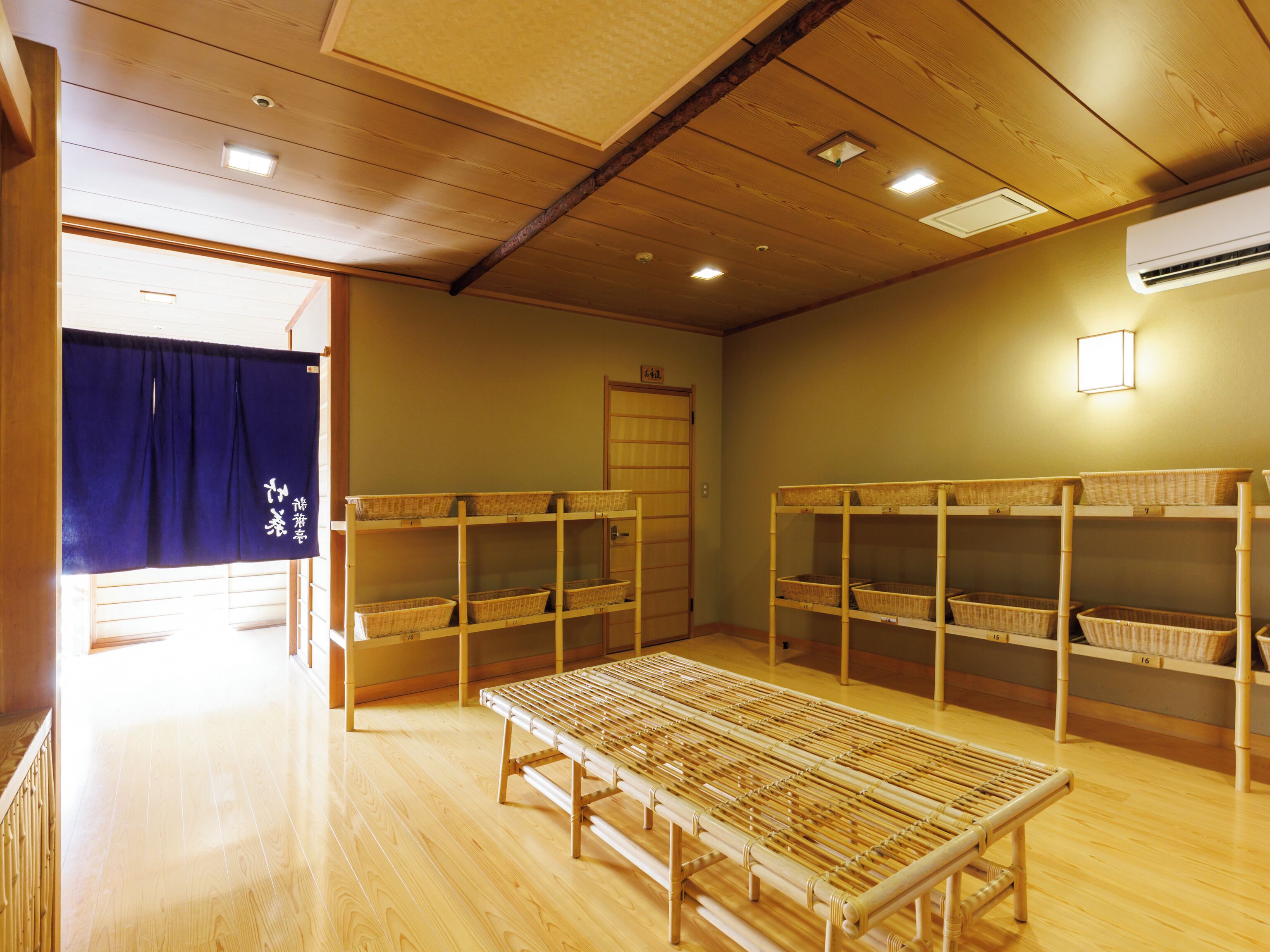 Une pièce avec un plancher en bois, un tapis en bambou et des étagères avec des paniers.