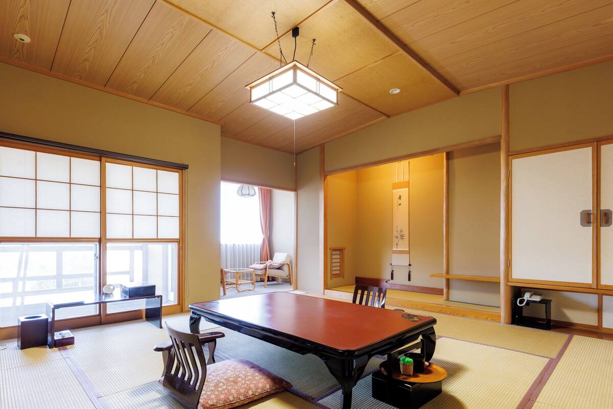 A traditional Japanese room with tatami flooring, a low table, and sliding doors.