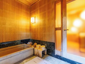 A wooden spa room with a bathtub, wooden stools, and a small wooden table. - Chikuba Shinyotei (Hakodate)
