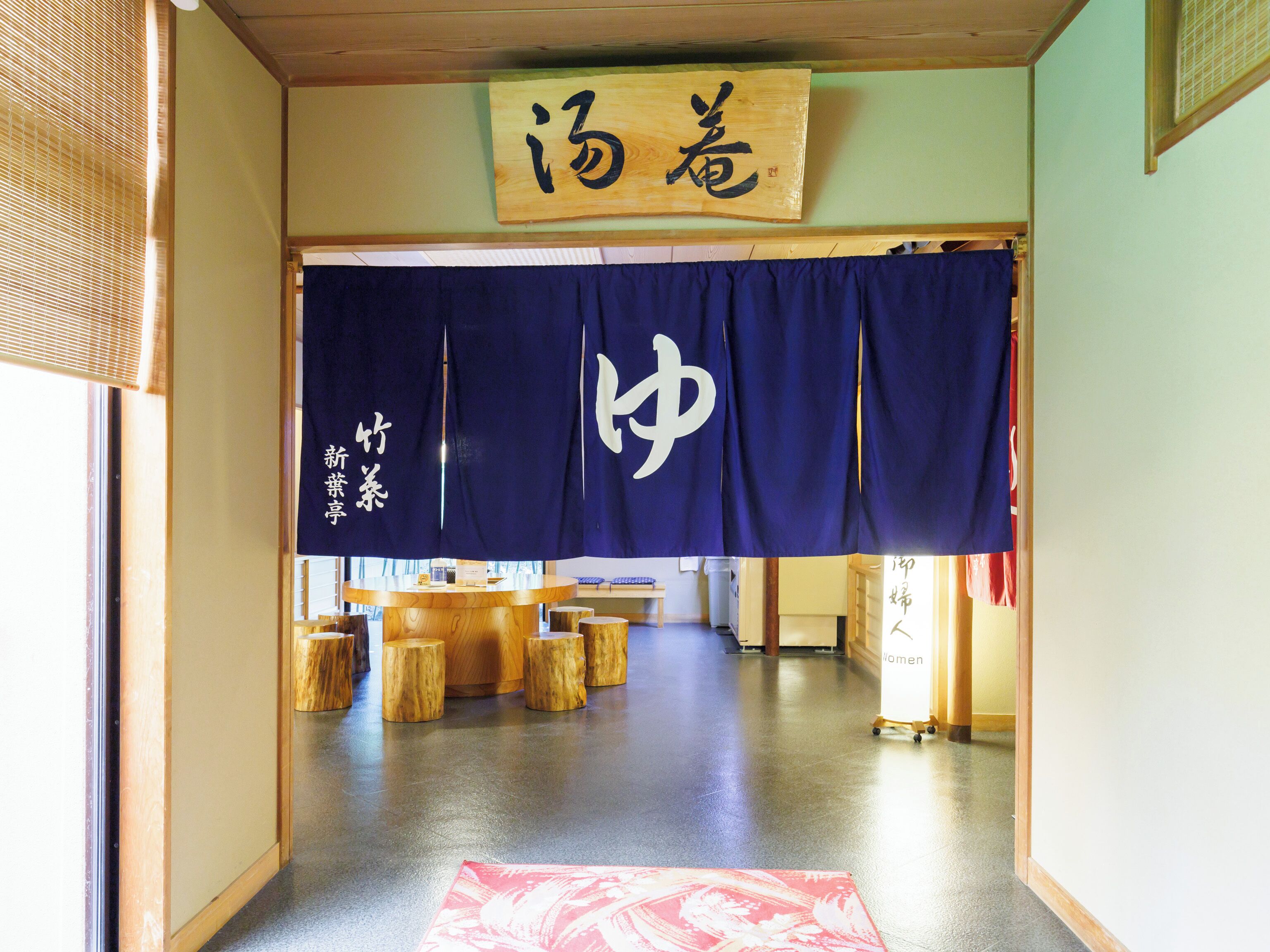 Un interior japonés tradicional con esteras de tatami, un mostrador de recepción de madera y un letrero con caracteres japoneses.