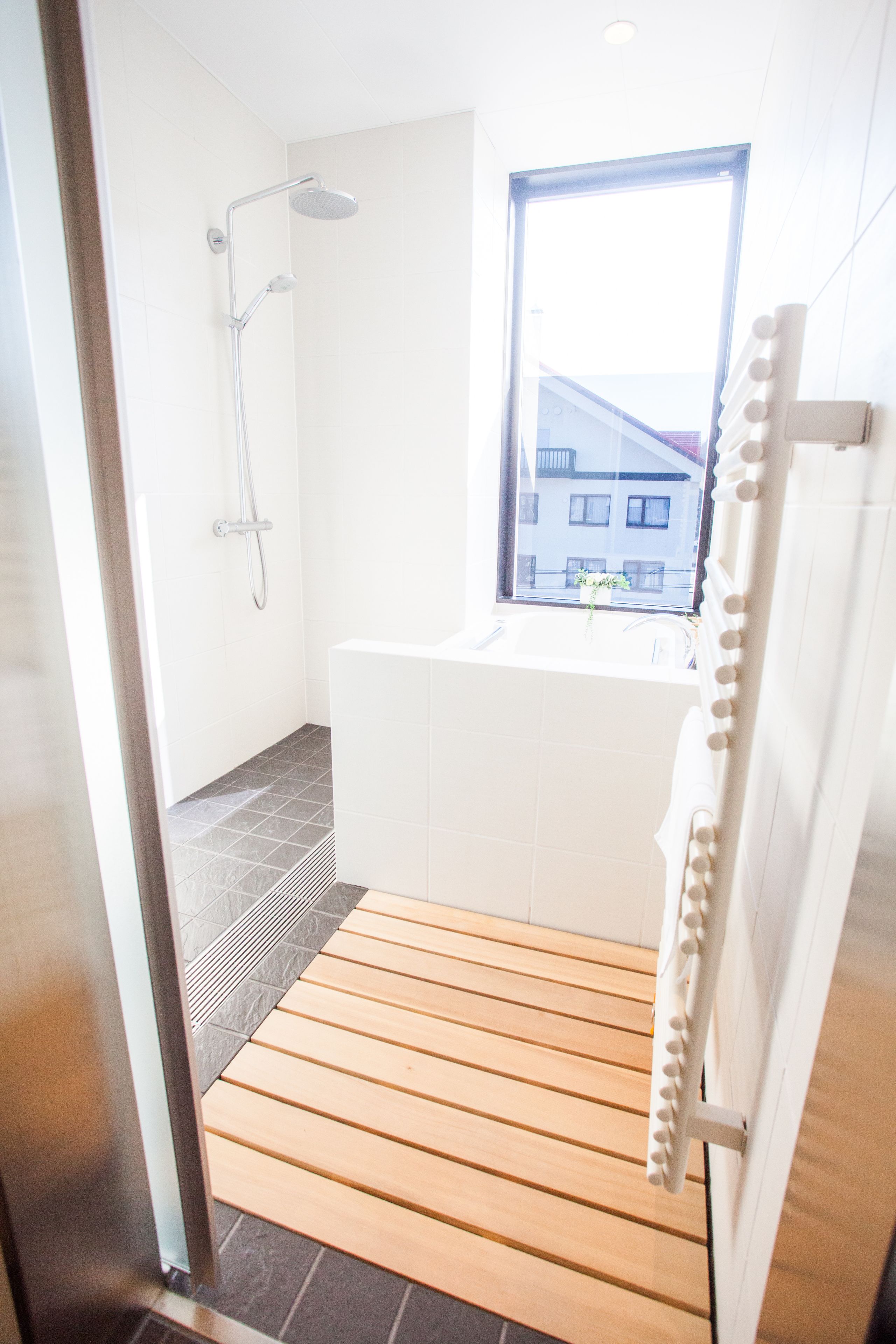 Une salle de bain moderne équipée d’une douche, d’une baignoire et d’une fenêtre donnant sur l’extérieur.