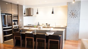 A modern kitchen with a central island, bar stools, and a built-in oven. - Hirafu 188 (Kutchan)