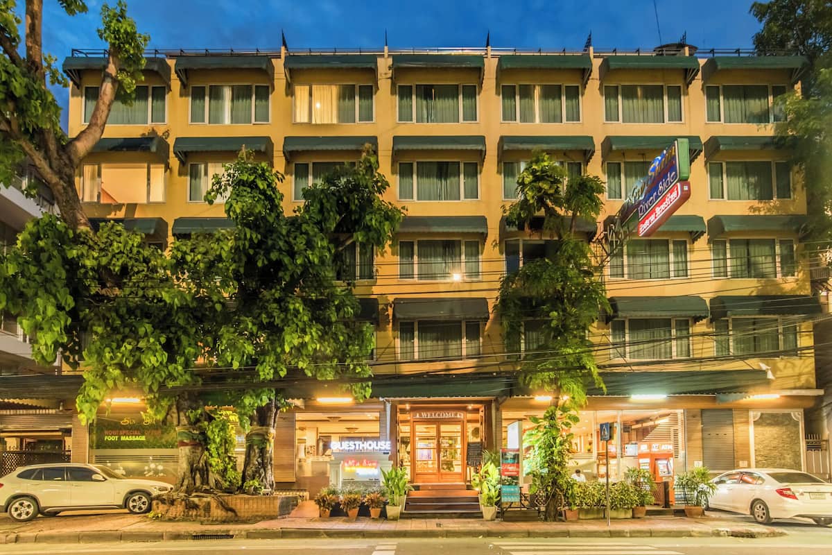 A multi-story hotel with a row of balconies, a visible guesthouse, and a foot massage service.