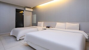 Una habitación de hotel con dos camas, una mesita de noche con un teléfono y un equipo de aire acondicionado.