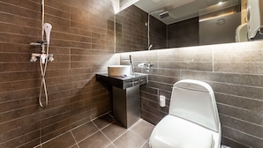 Un baño moderno con ducha, lavamanos e inodoro.