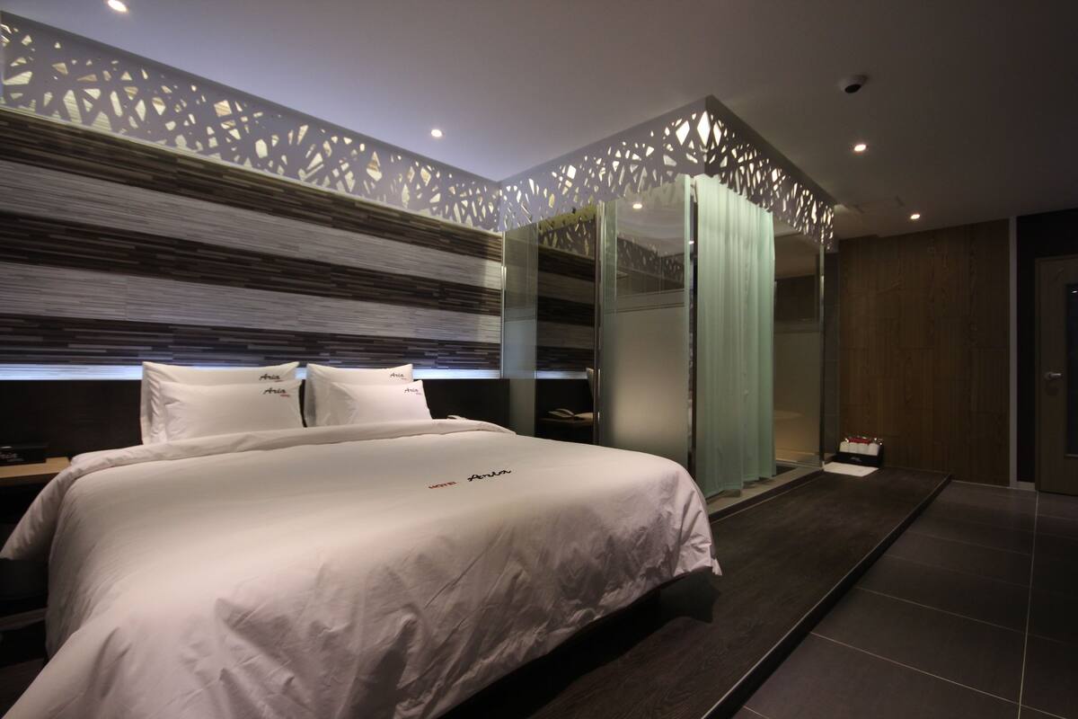 A modern bedroom with a large bed, a walk-in closet, and a decorative ceiling.