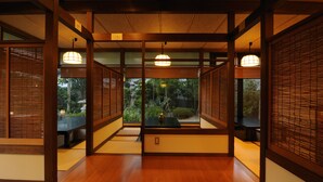 A traditional Japanese room with tatami flooring, sliding doors, and a view of a garden. - Kifu No Sato (Mimasaka)