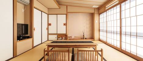 Una habitación japonesa tradicional con suelo de tatami, una mesa baja, cojines, puertas correderas y un televisor.