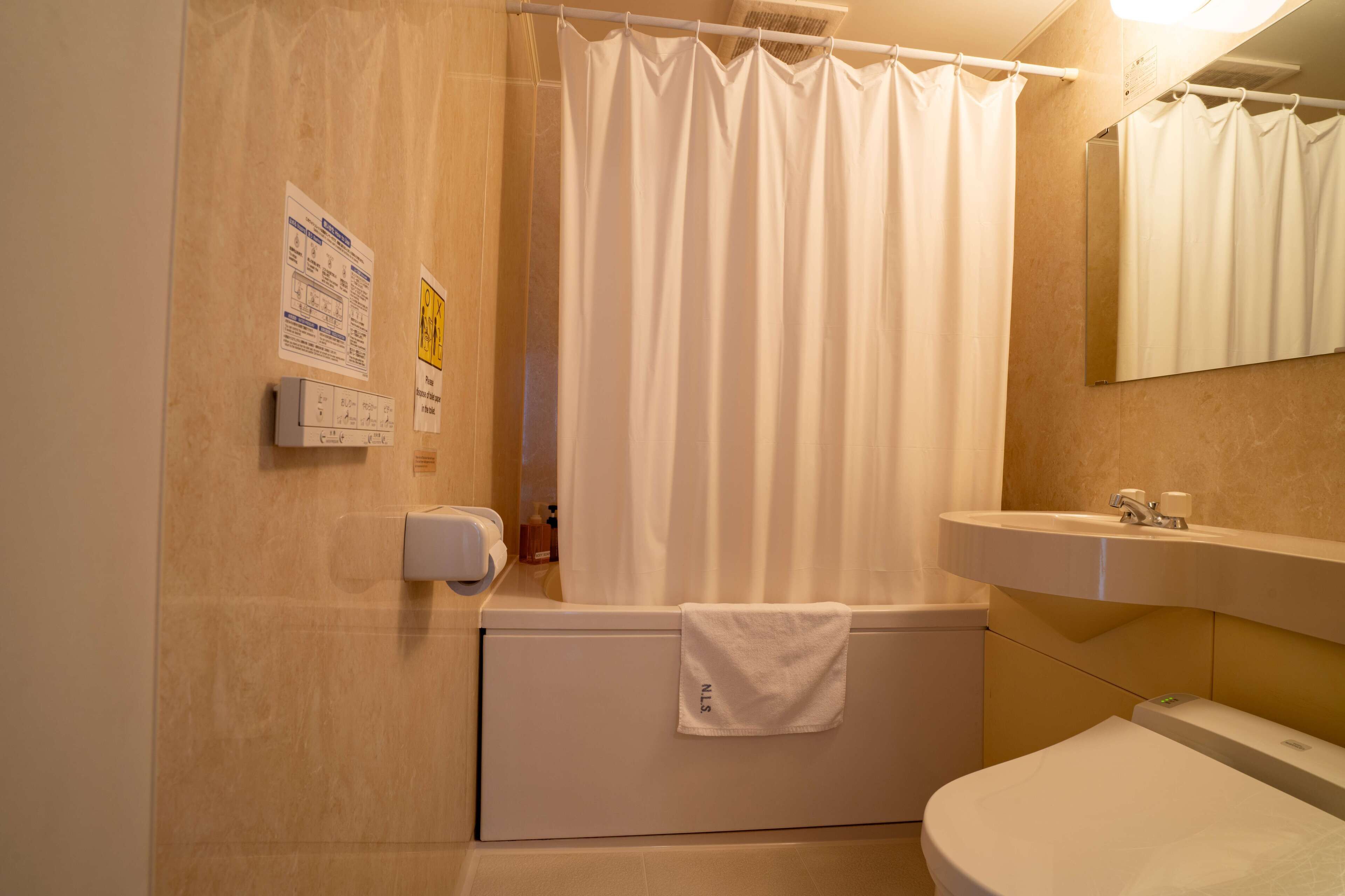 Une salle de bain avec une baignoire, un lavabo et un miroir. Il y a des panneaux sur le mur et une serviette est accrochée à la baignoire.