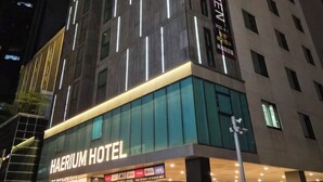 A modern hotel building with illuminated signage, large windows, and a prominent entrance. - Haerium Hotel (Busan)