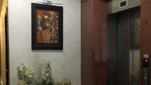 An elevator with a digital display, a framed artwork on the wall, and a potted plant with flowers. - Huong Mai 2 Hotel (Ho Chi Minh City)