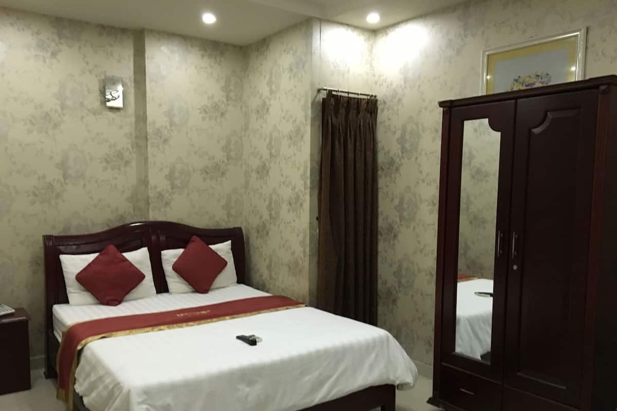 A bedroom with a bed, a wardrobe, and a mirror.