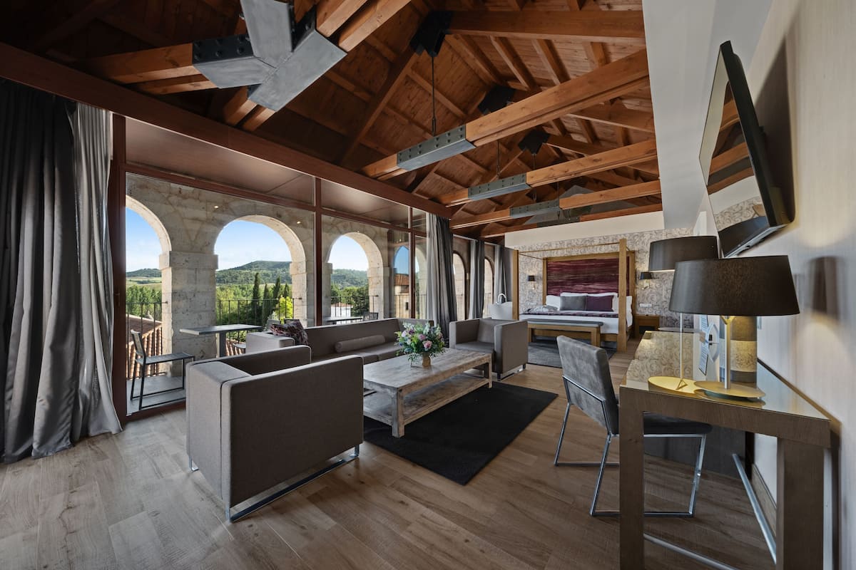 A modern living room with a wooden ceiling, large windows, and a stone archway.