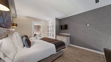 Une chambre d’hôtel moderne dotée d’un grand lit, d’un bureau, d’une télévision à écran plat et d’une salle de bain visible à travers une porte ouverte.