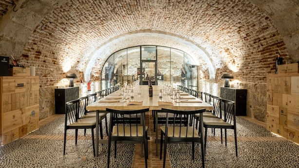 A long table set for dining in a room with arched brick ceilings and wooden panel walls.