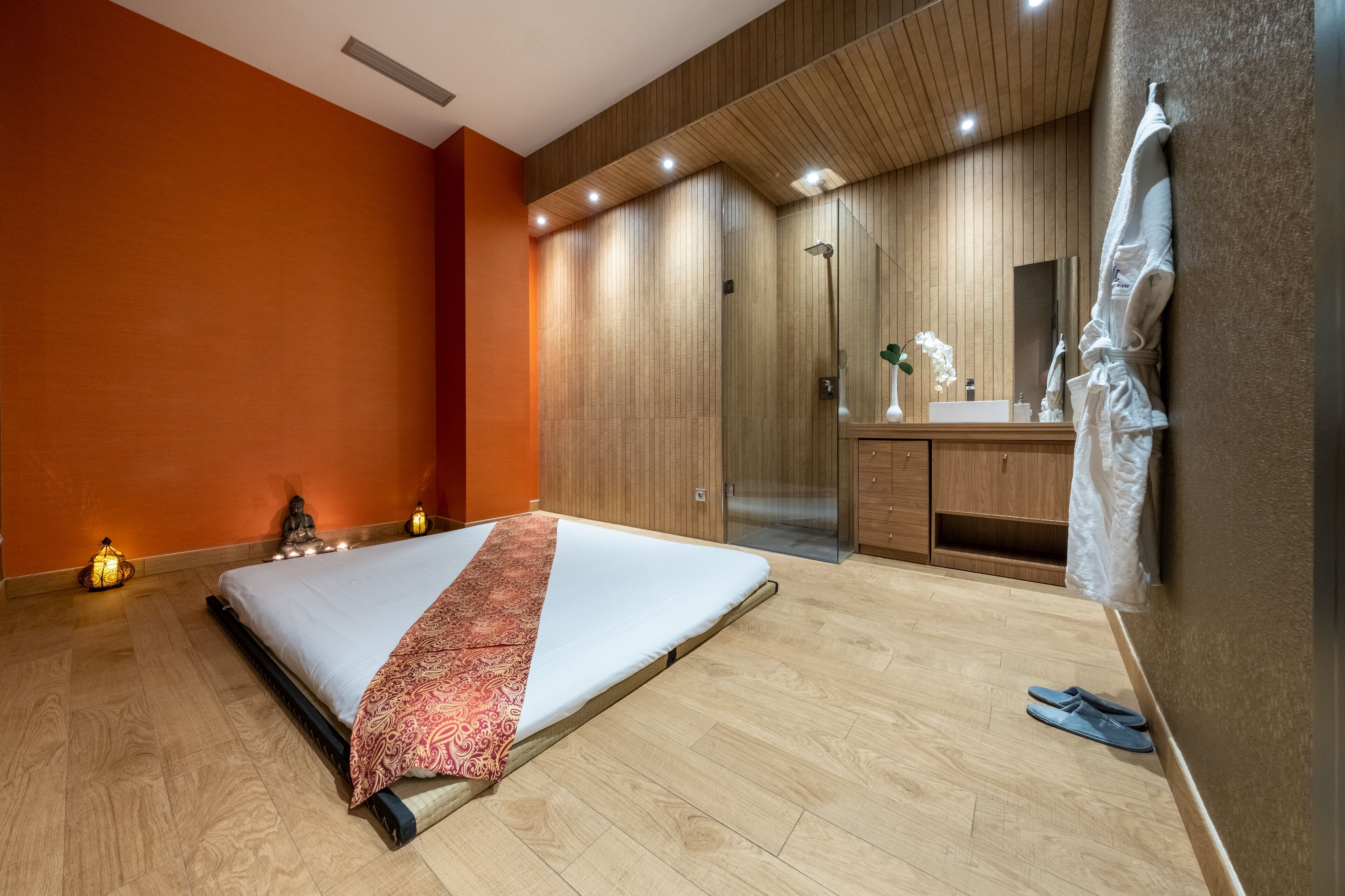 A modern bedroom with a bed, wooden wardrobe, and a bathroom with a mirror and sink.