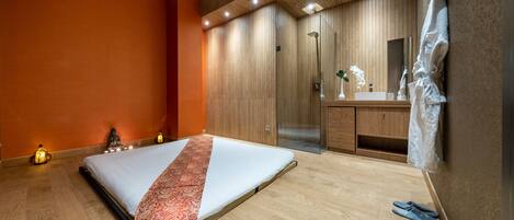 A modern bedroom with a bed, wooden wardrobe, and a bathroom with a mirror and sink.