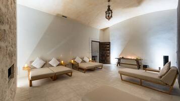 Una habitación amplia con techo alto, chimenea y zona de estar con cojines y una mesa.