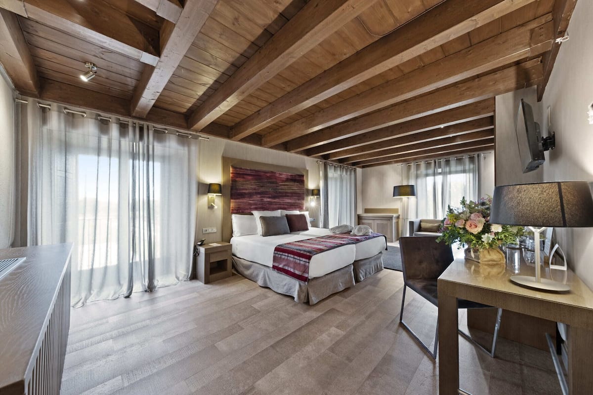 A modern bedroom with a wooden ceiling, a large bed, a desk, and a chair.