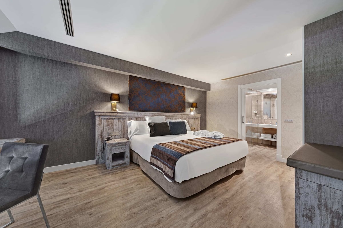A modern bedroom with a large bed, bedside tables, a chair, and a walk-in closet.