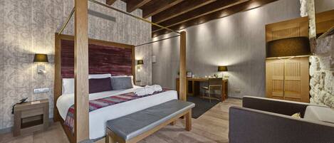 Un dormitorio con cama con dosel, un escritorio, una silla y un banco.