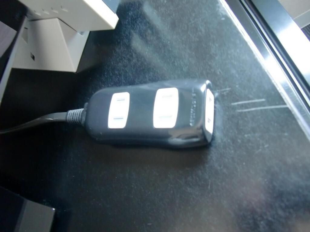 Un objeto negro con un cable sobre una superficie oscura.