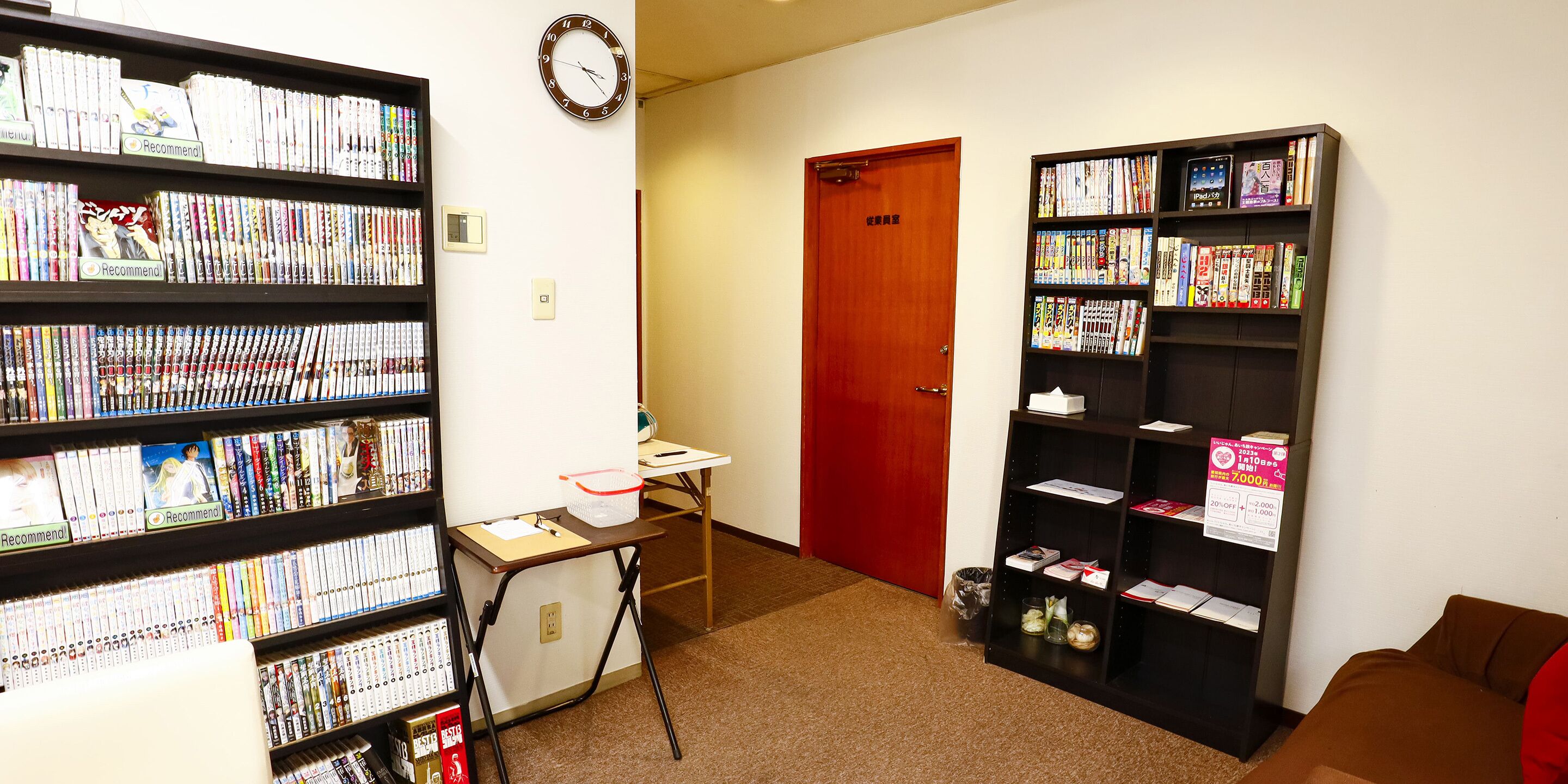 Eine Bibliothek mit Bücherregalen, einem Schreibtisch und einer roten Tür.