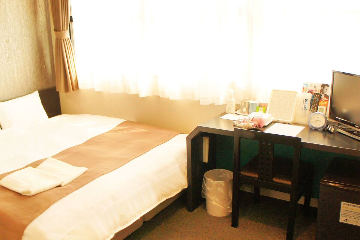 Ein Hotelzimmer mit einem Bett, einem Schreibtisch, einem Stuhl, einem Fernseher und einem Mülleimer.
