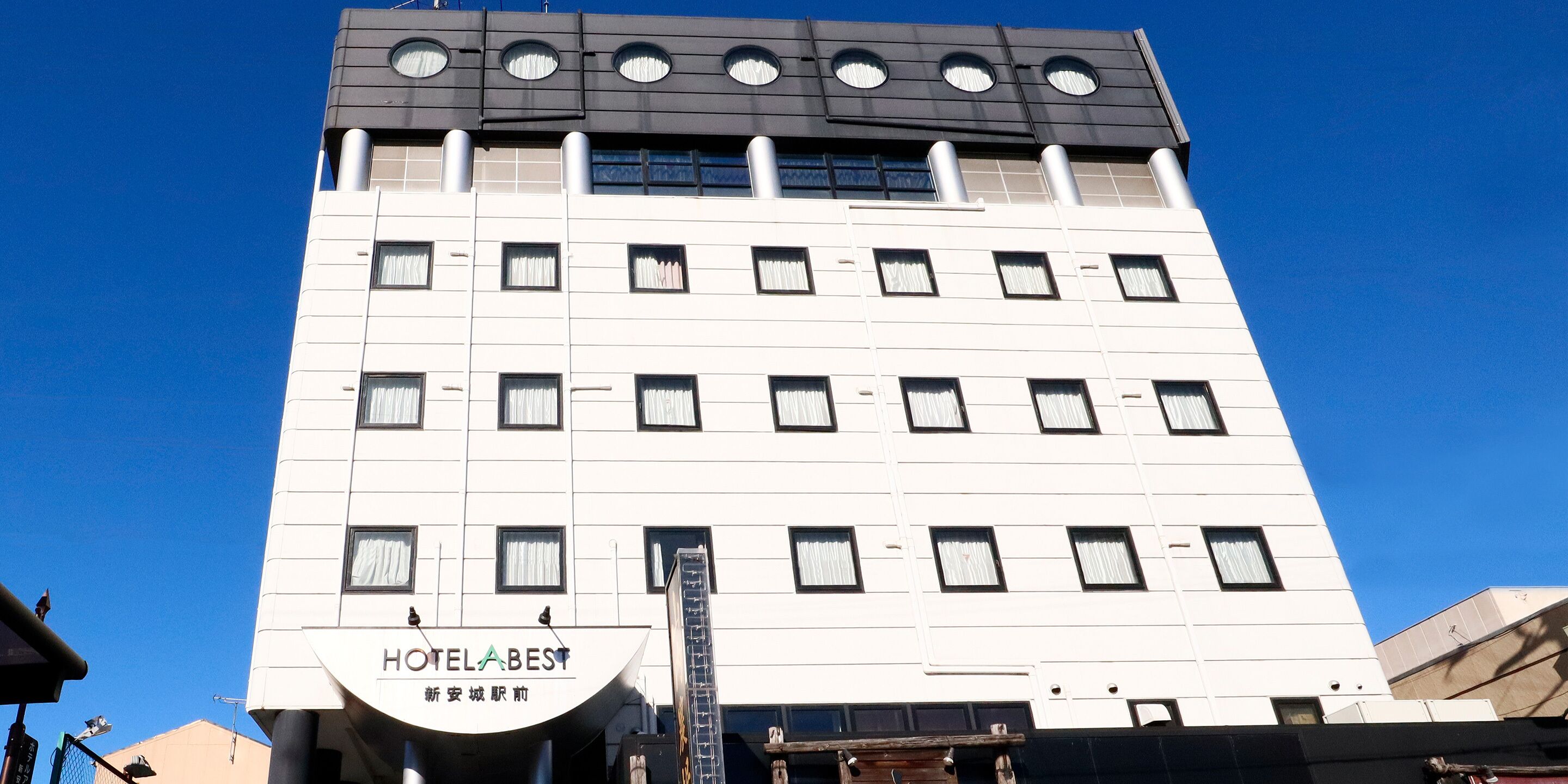 A multi-story hotel with a modern facade, featuring a prominent sign for HOTELABEST.
