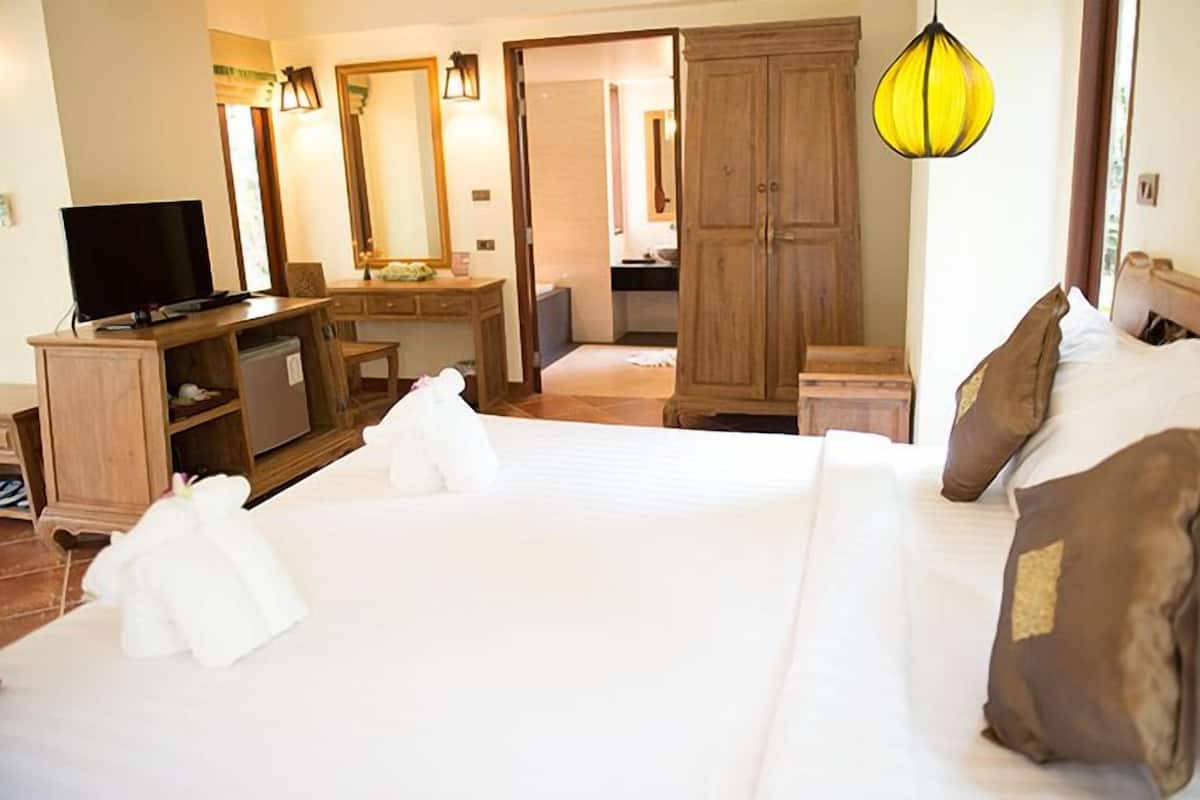 A hotel room with a bed, a desk, a television, and a wardrobe.