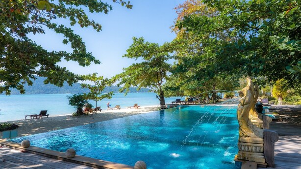 A pool with a water feature, surrounded by lounge chairs and a view of the sea. - Chivapuri Beach Resort (Ko Chang)