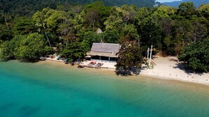 A beachside resort with a thatched-roof building, clear turquoise waters, and dense forest surrounding the property. - Chivapuri Beach Resort (Ko Chang)