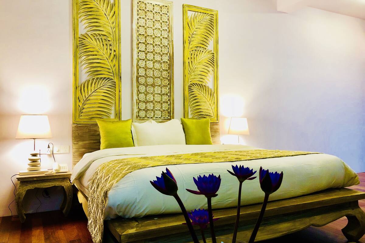Quarto com cama, duas mesas de cabeceira e painéis decorativos na parede.