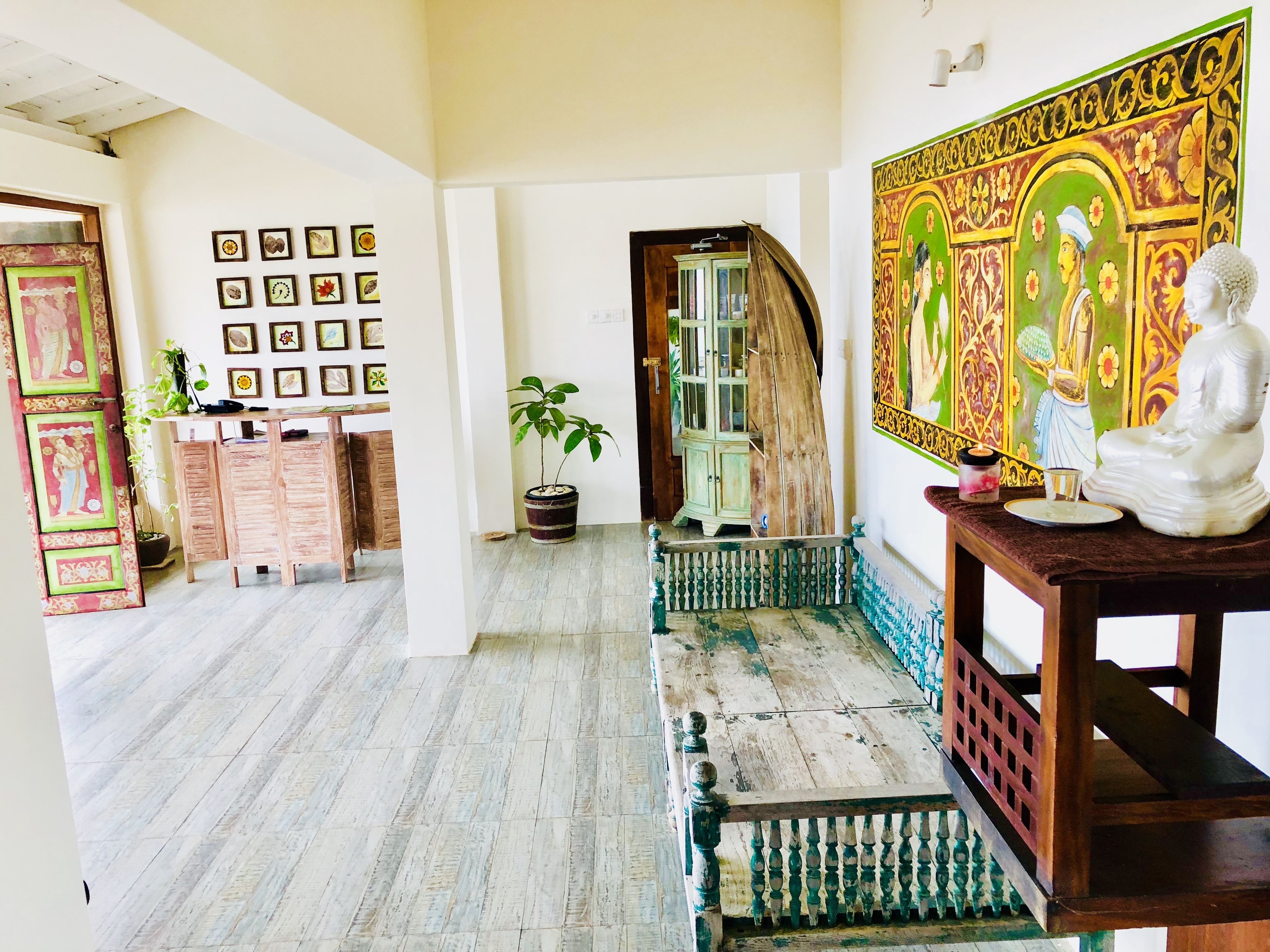 Una habitación con suelo de madera, un banco, una estatua y una pared con cuadros enmarcados.