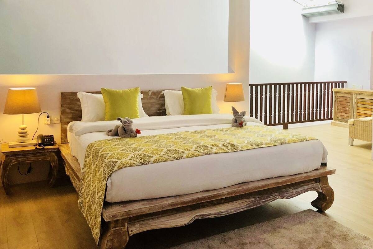 Quarto com cama de madeira, duas luminárias de cabeceira, um ventilador de teto e vista do céu.